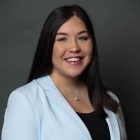 Headshot of Brittany Stansel, wearing a blue blazer with a dark background