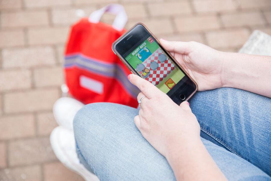 A student holds an iPhone and plays a game.