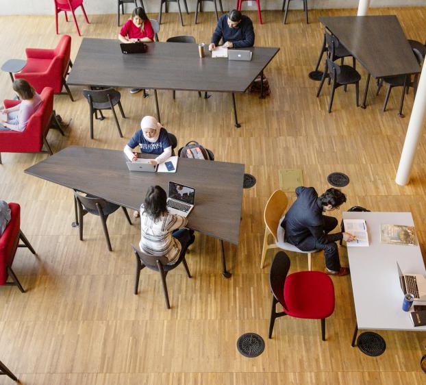 An aerial view of students sitting at table and in chairs studying and hanging out in Munday Library.
