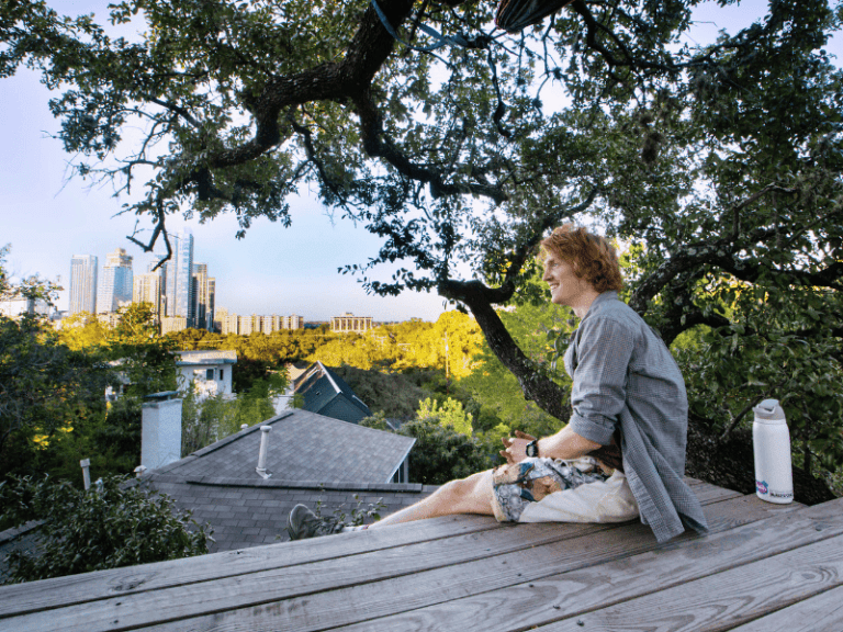 Ethan Burd sits on his home treehouse with a view of the Austin skyline