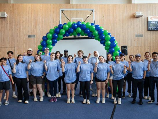 Student leaders in blue shirts helping with Orientation in the alumni gym.