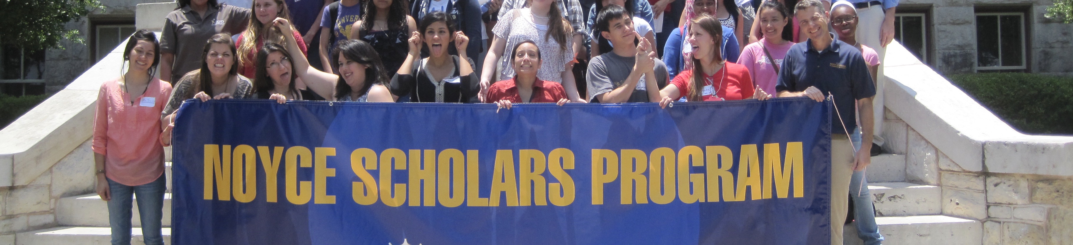 students posing with Noyce banner at red doors