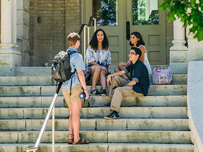 Students chat on the steps of Holy Cross Hall at St. Edward's University 