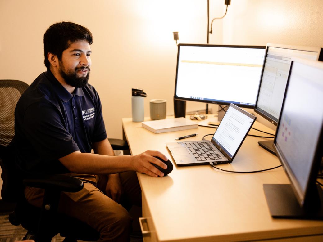 A staff member sits at their desk and works on their computer.