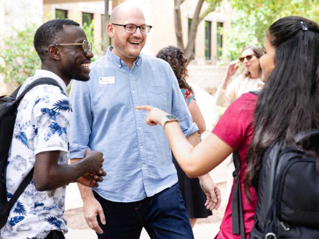 An admissions counselor talks with international students at an event.