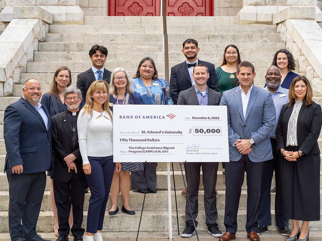 A group of business leaders, students and university administrators accept a check on the steps in front of Main Building.