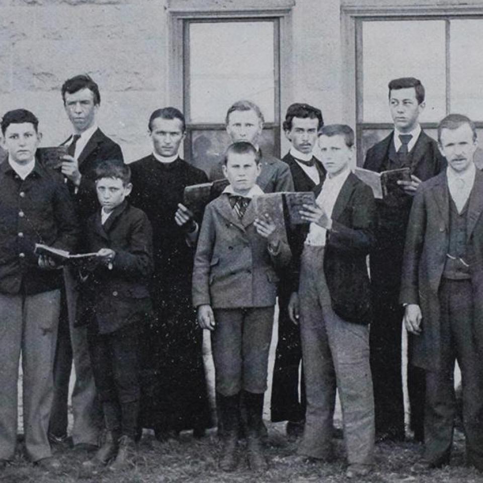 A group of classmates and brothers posing in a makeshift building in 1878 