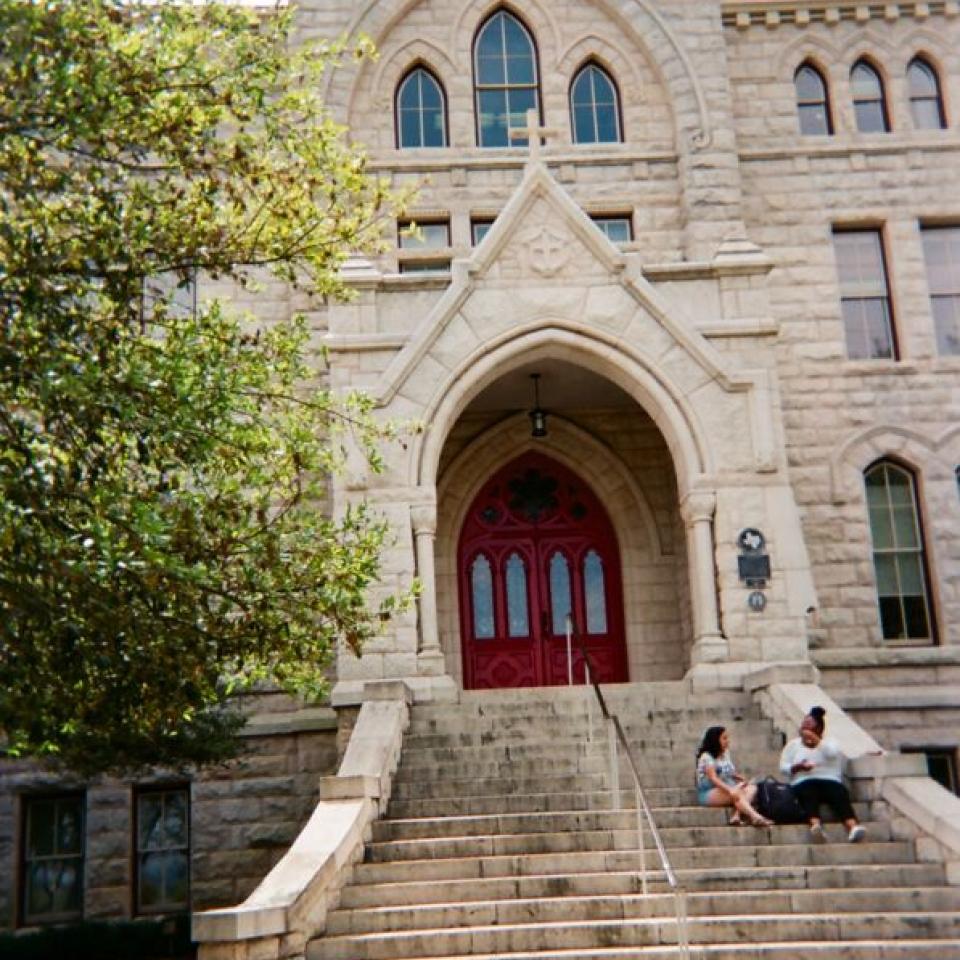 Two students sit on the steps of Main Building.