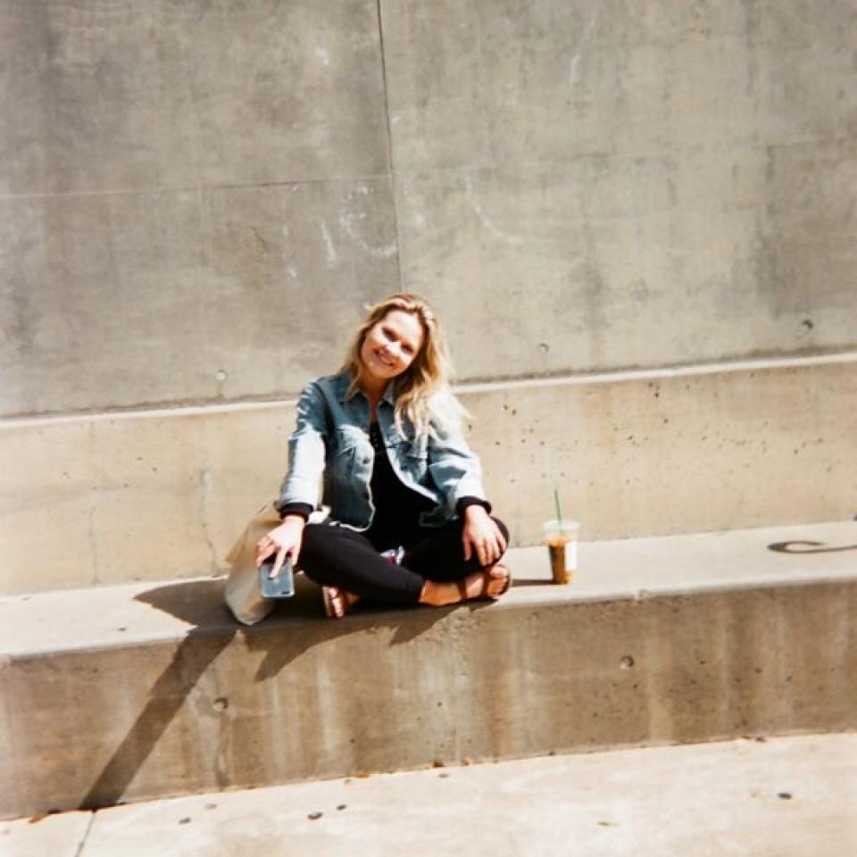 A student sits on a concrete bench at Trustee Hall.