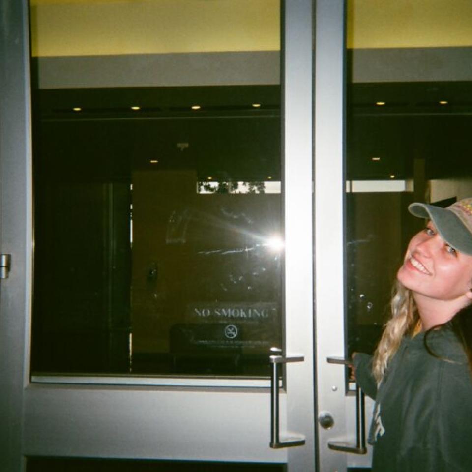 A student stands outside of a door on campus.