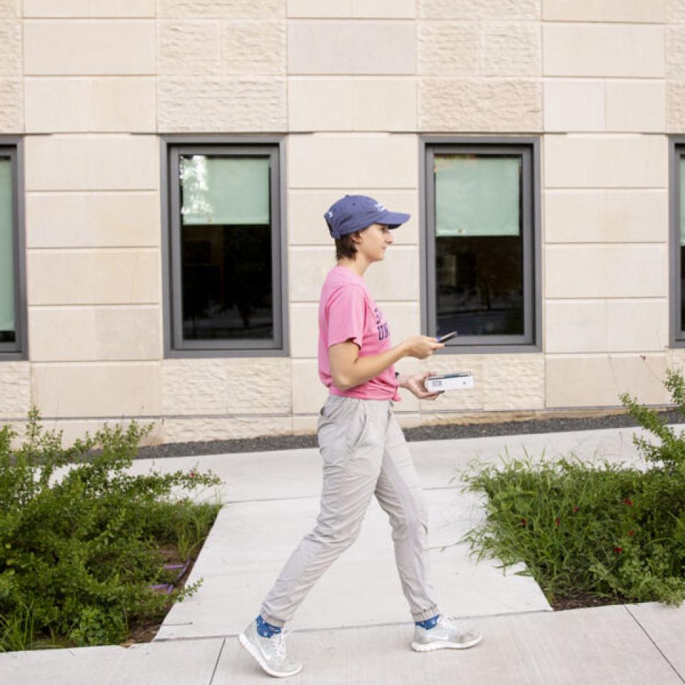 Stella Cunngham walks up a path with windows behind her.