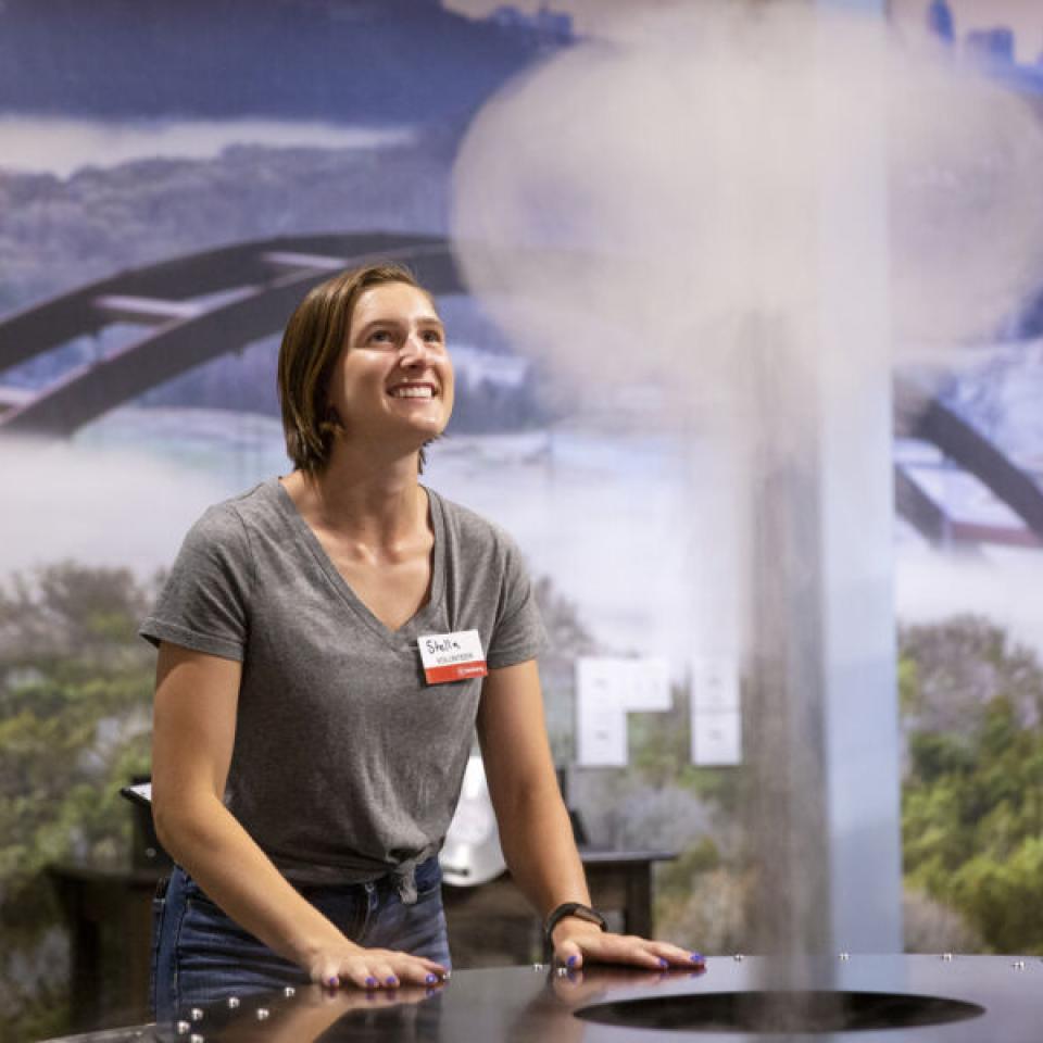 Stella Cunningham interacts with an exhibit while volunteering at The Thinkery.