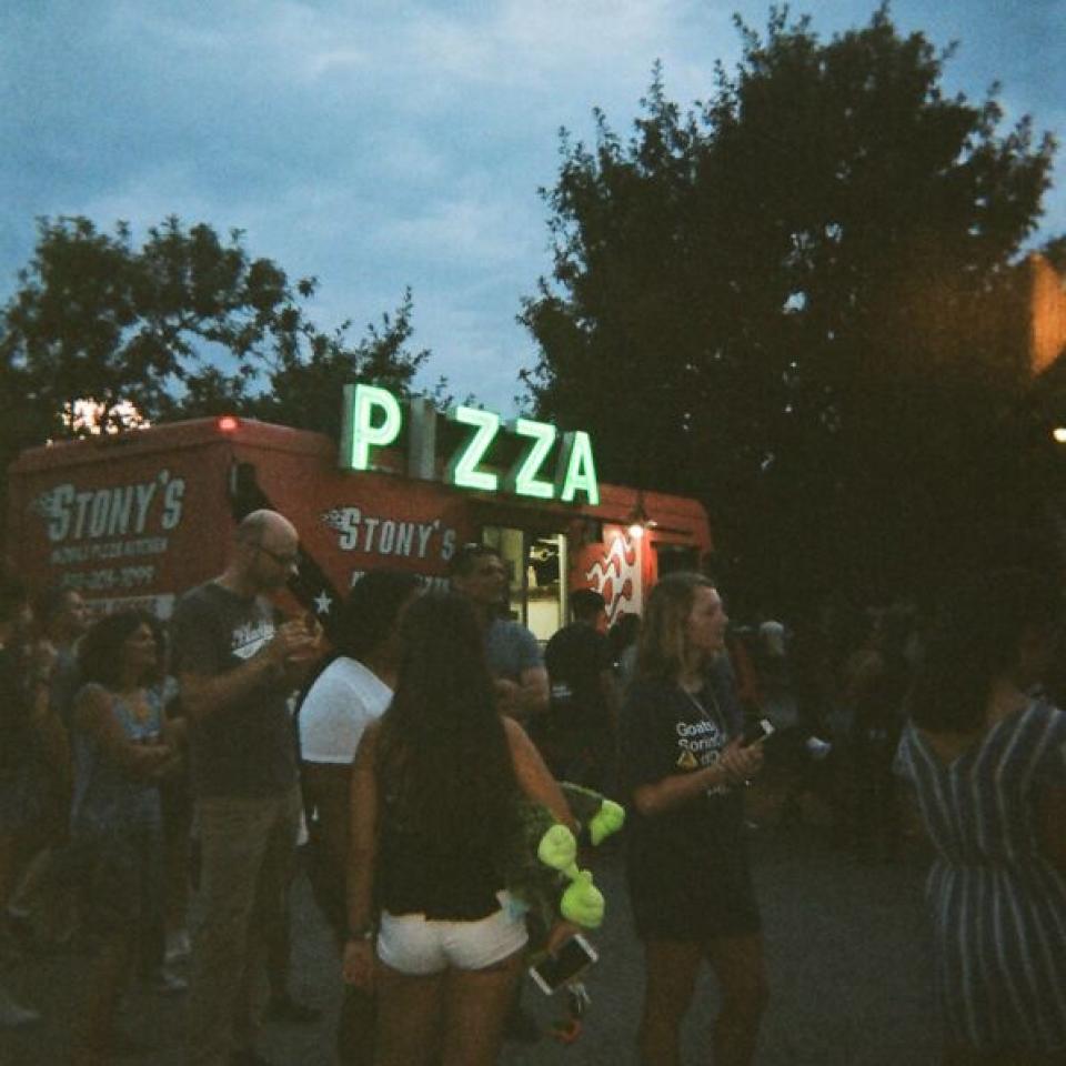 People stand around a pizza food truck.