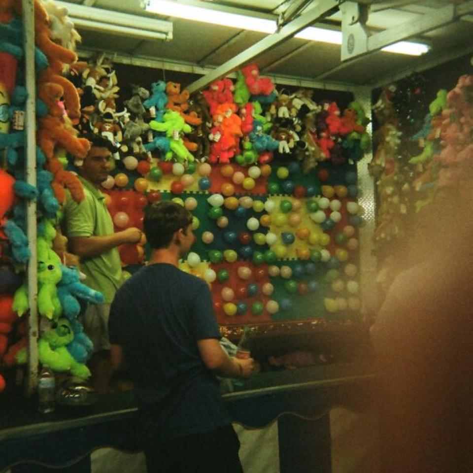 A person stands near a carnival game.