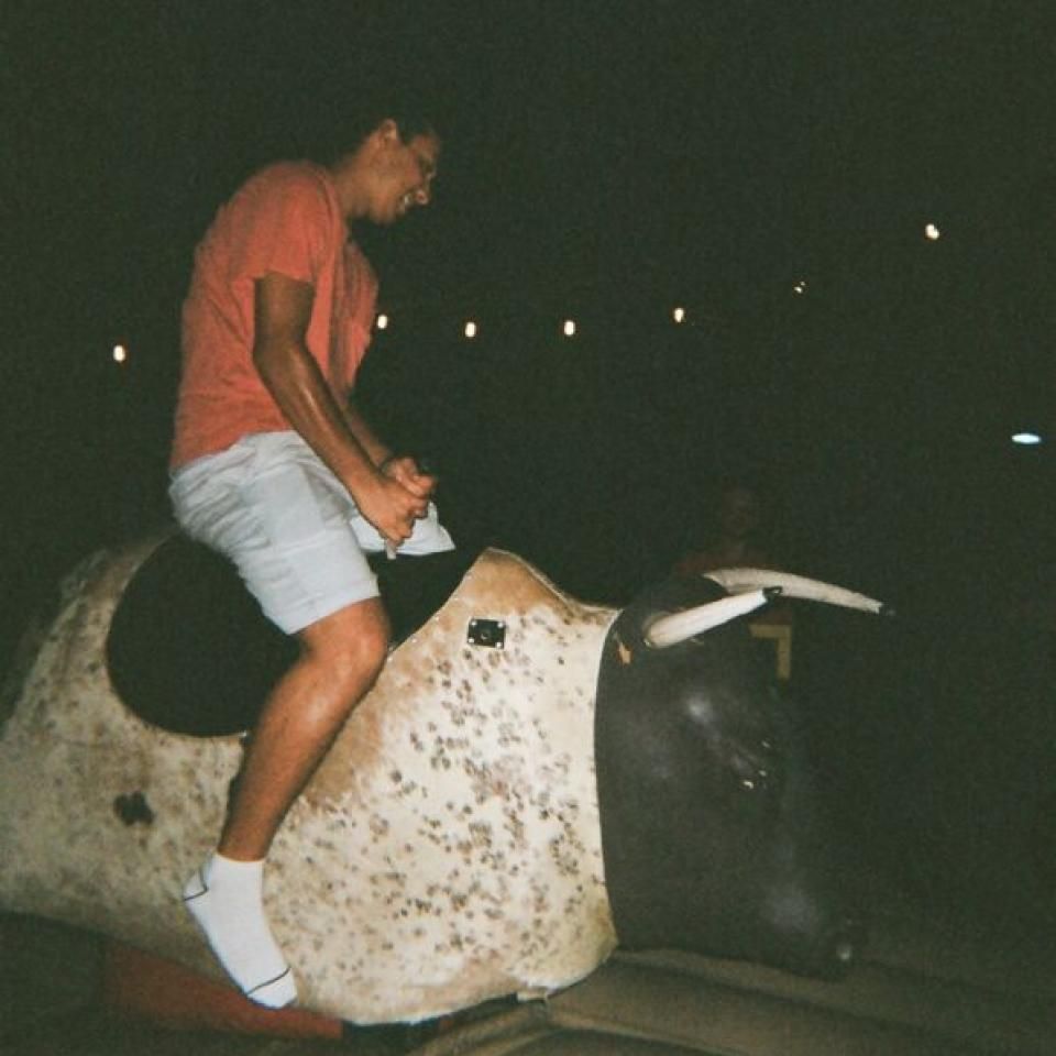 A student rides a fake bull on an inflatable.