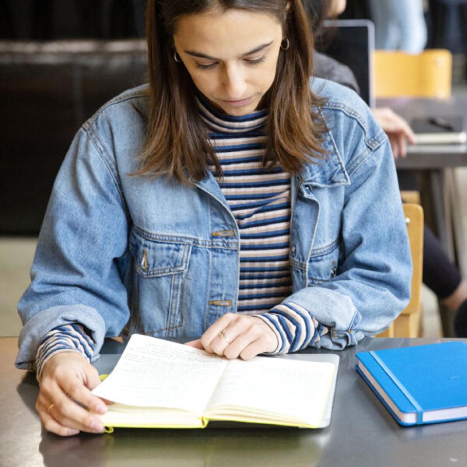 Student studying and reading a book on campus.