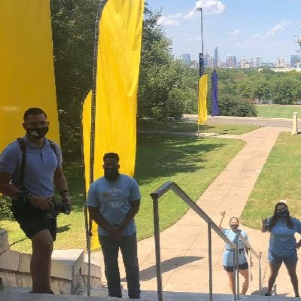 Staff and student leaders stand on Main Building steps wearing face masks.