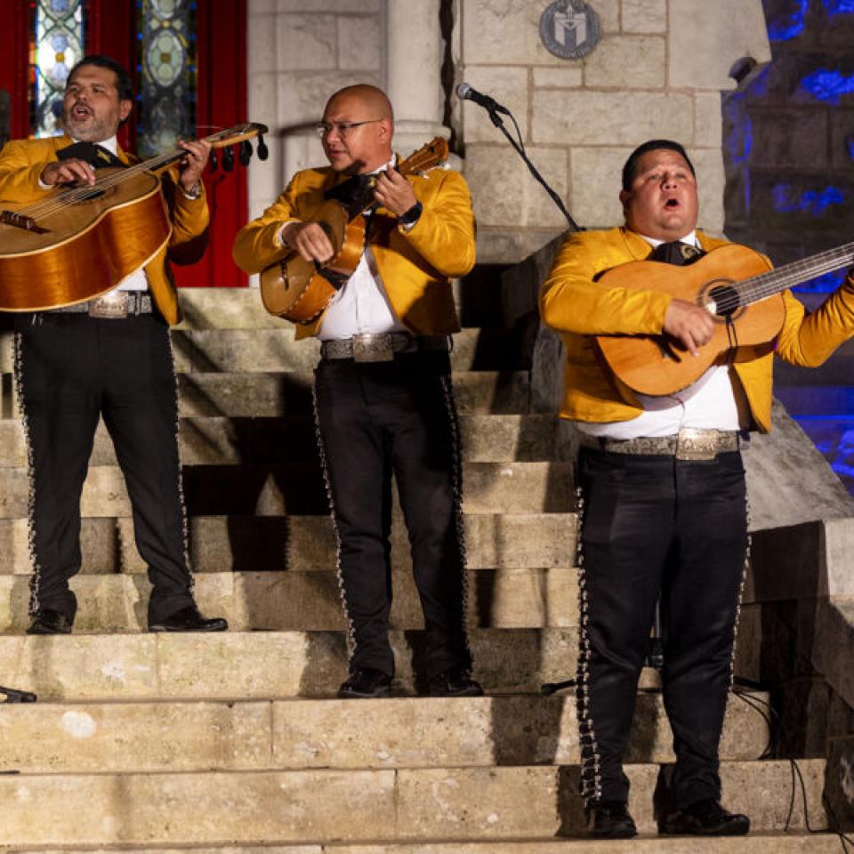 Three mariachi singers holding acoustic guitars