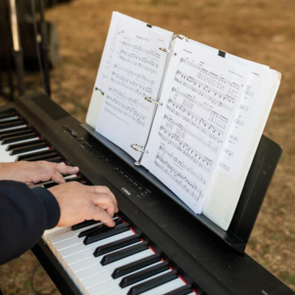 Person playing the keyboard while reading off a sheet of music.