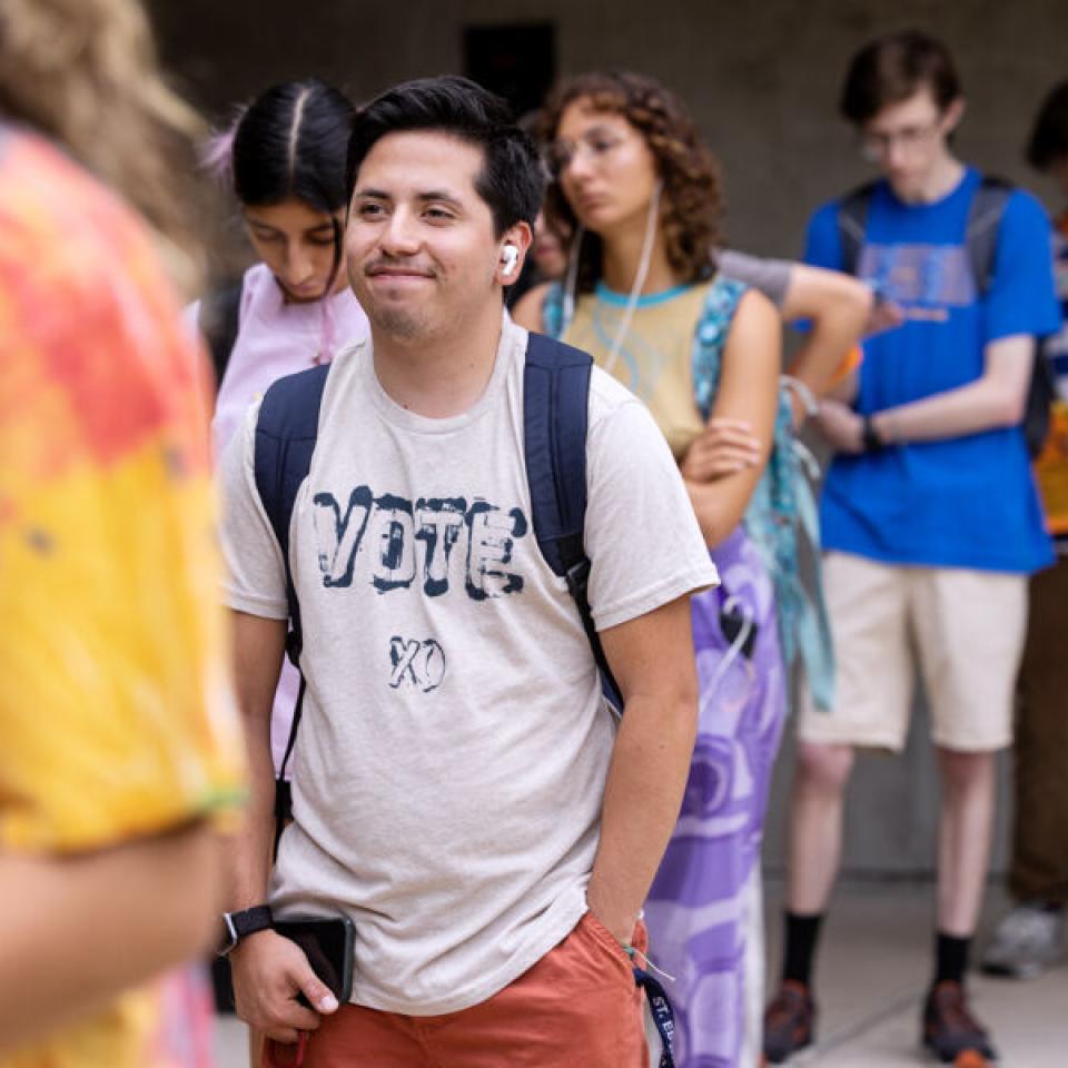 Ethan Tobias wears a shirt that says "Vote" while standing in line to vote on campus.