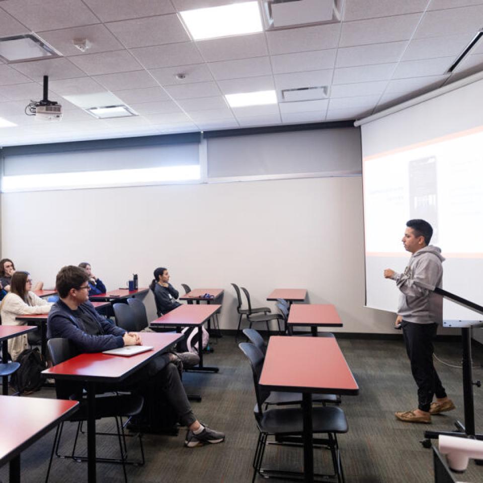 Ethan Tobias stands at the front of a classroom in Equity Hall and shares a presentation with classmates.