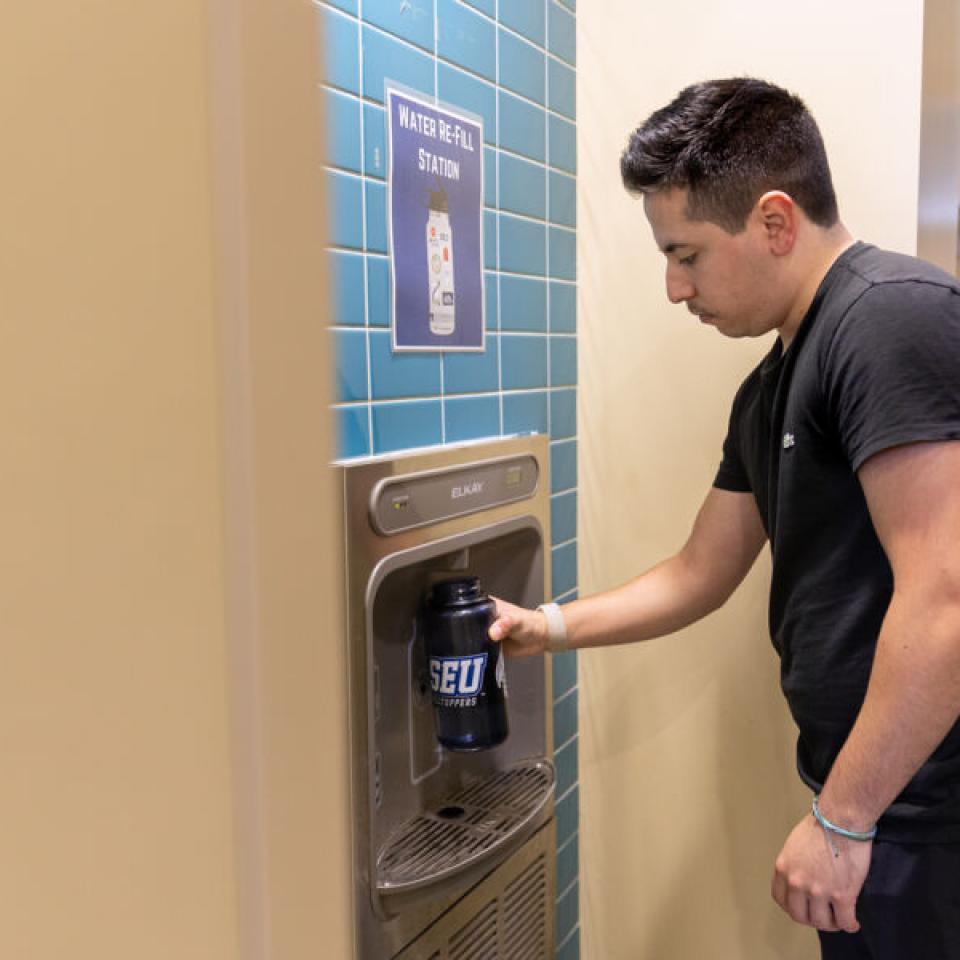 Ethan Tobias uses a refillable water station to fill his SEU branded water bottle.