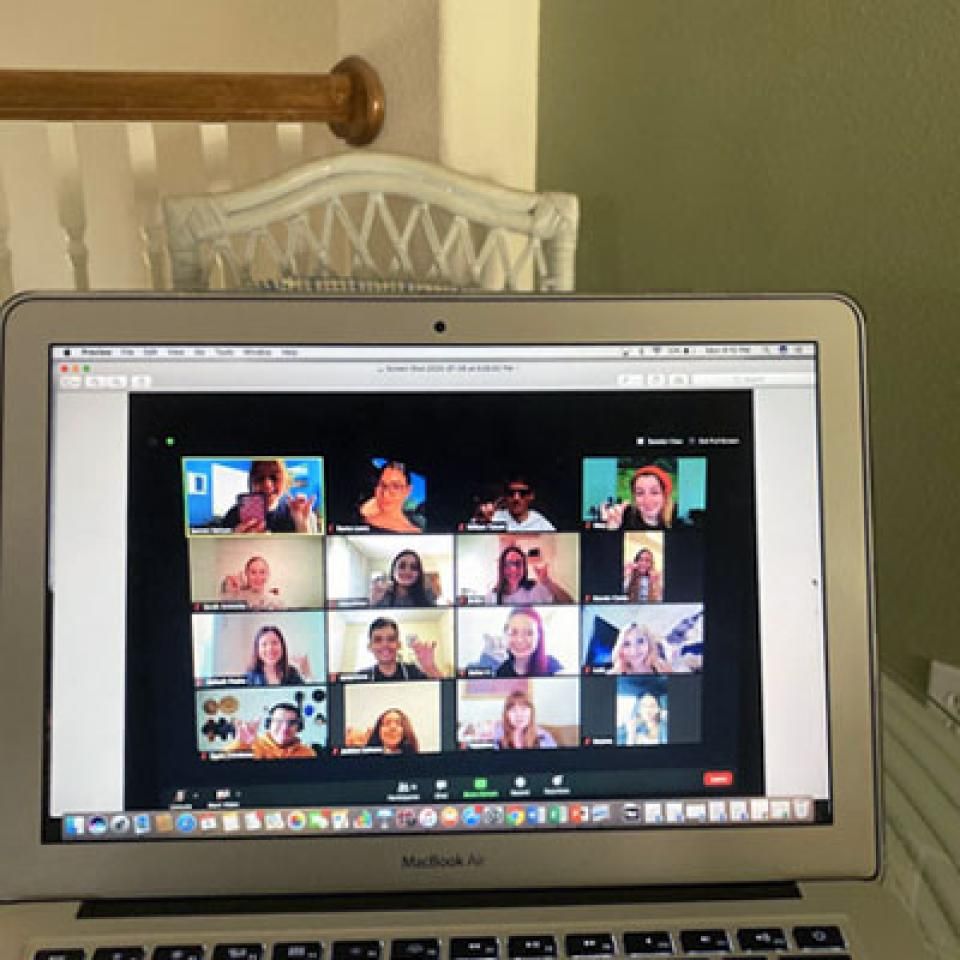 A zoom meeting of faces on a laptop.