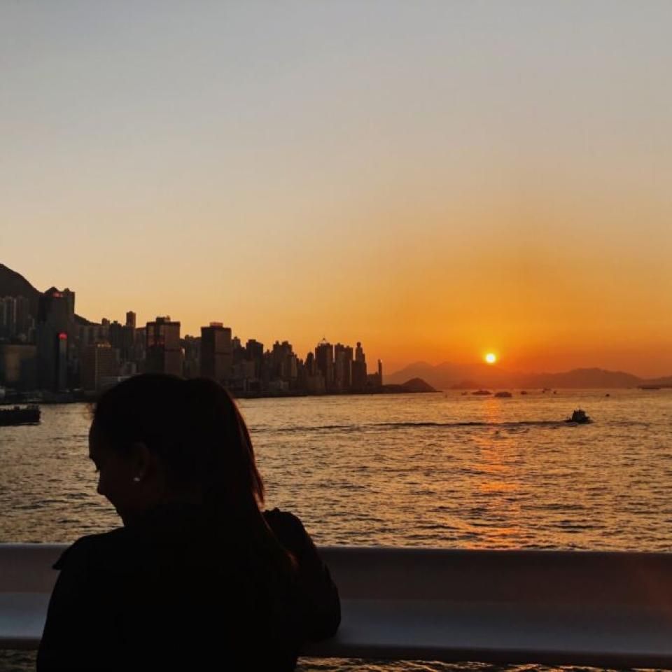 Aida Domingo is silhouetted by a sunset over the water.