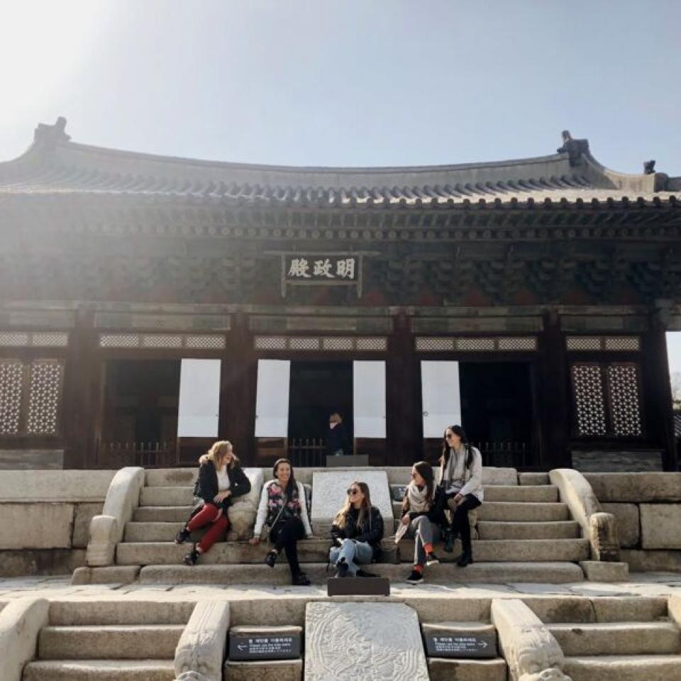 Aida Domingo and friends sit on the steps of a building.