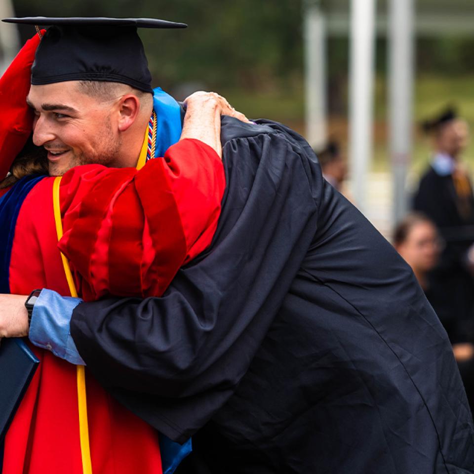 Graduate hugging professor at Spring Commencement 2023 