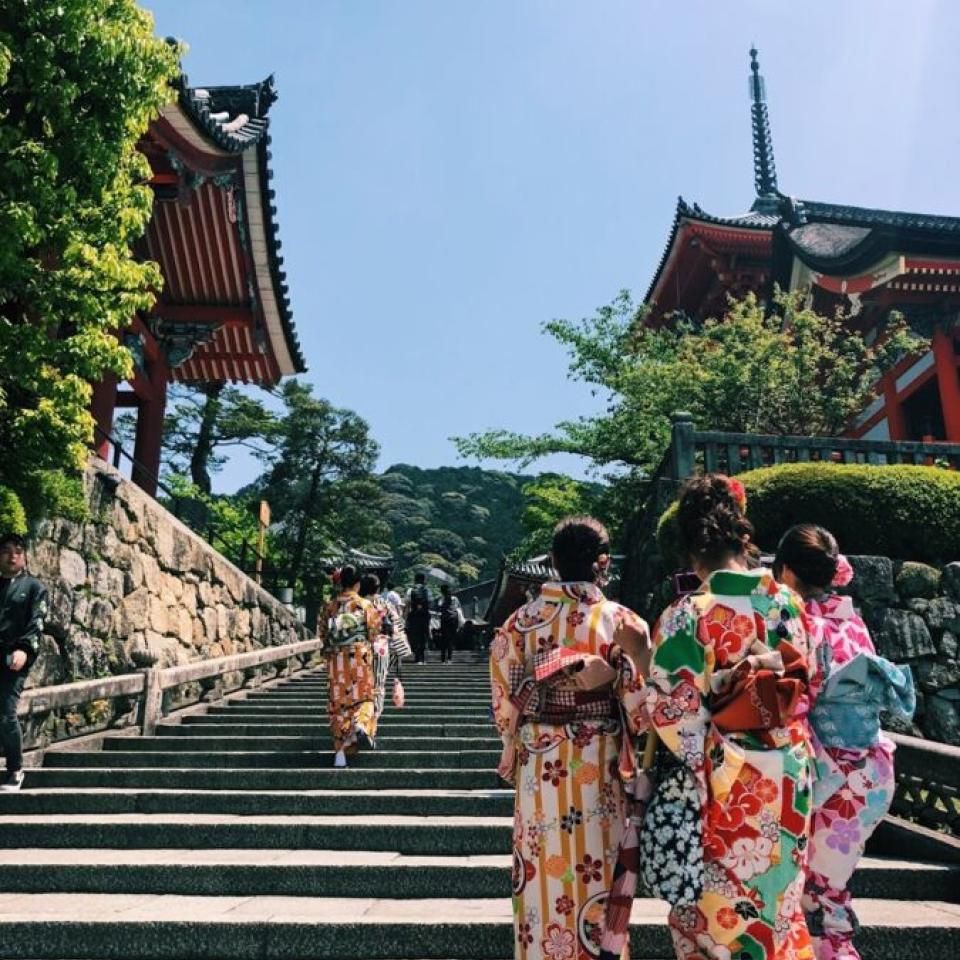 People wearing traditional dress walk up steps.