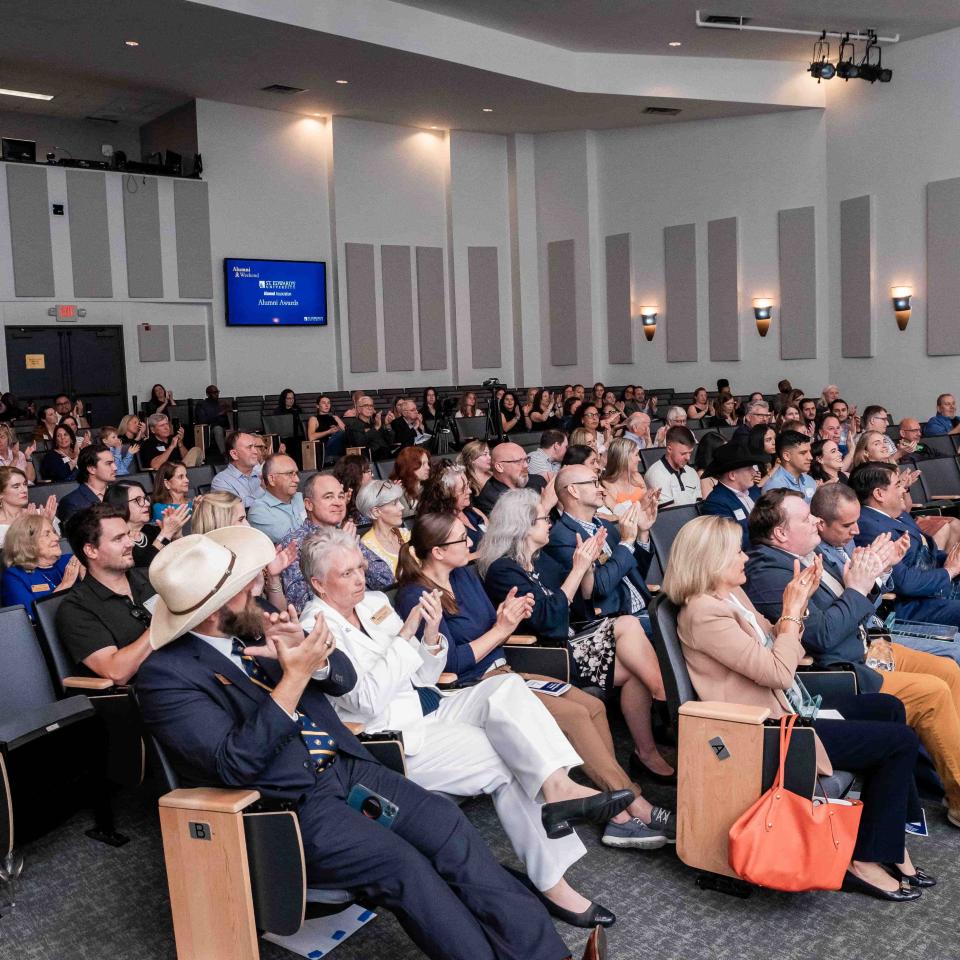 A group of people is seated in auditorium seating watching a presentation in Jones Auditorium