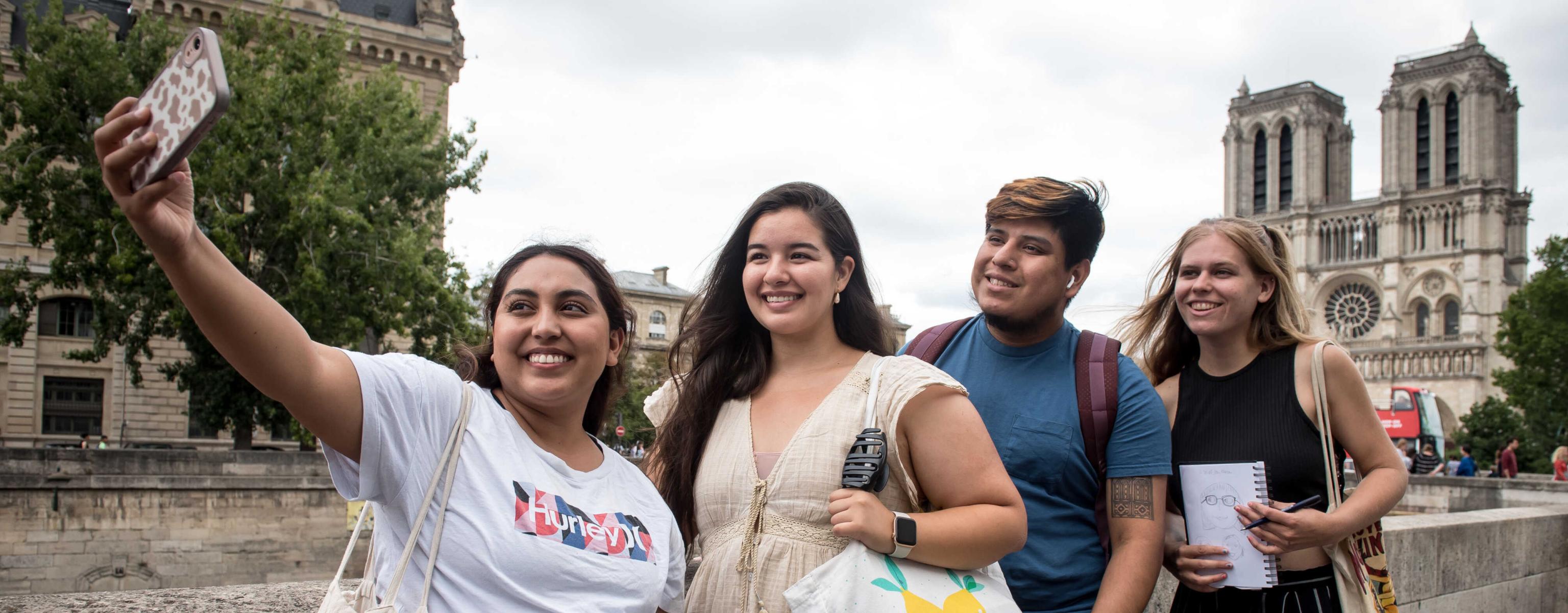 Students taking a group photo in front of the Cathédrale Notre-Dame de Paris during their study abroad trip.