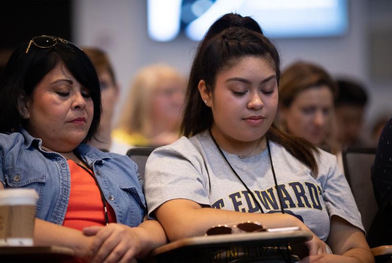 student and parent praying at orientation