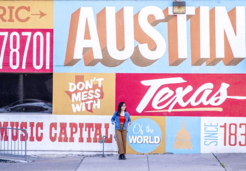 A St. Edward's student in front of a mural in downtown Austin, Texas