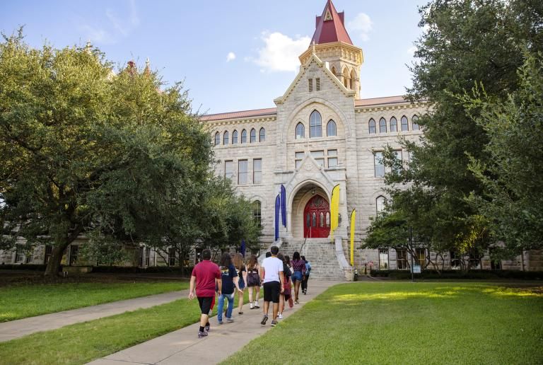 A group of new students walk towards the red doors of Main Building during the Legacy Walk.