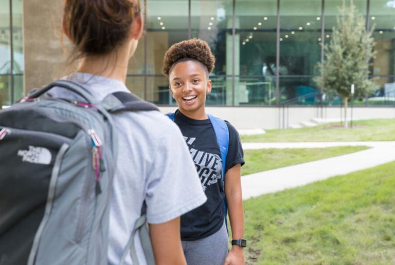 A student stands and talks with a friend outside of St. Andre Apartments.