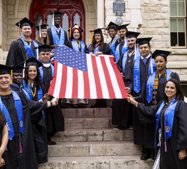 St. Edward's University veterans with the United States flag in front of Main Building.