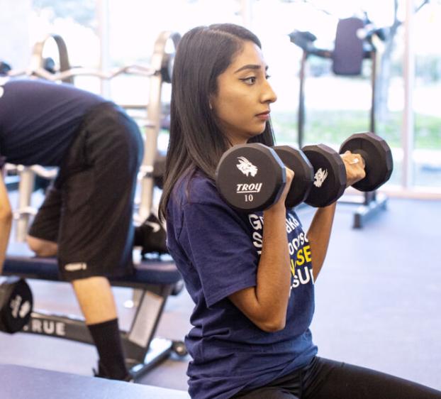 A student lifting weights in the Recreation and Wellness Center gym at St. Edward's University