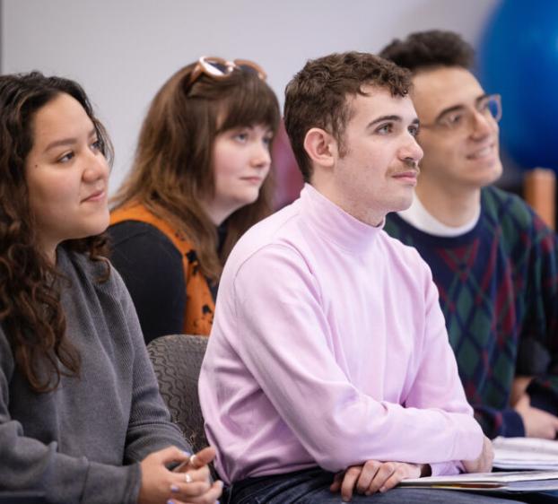 Four theatre students sit and listen to a guest lecturer.