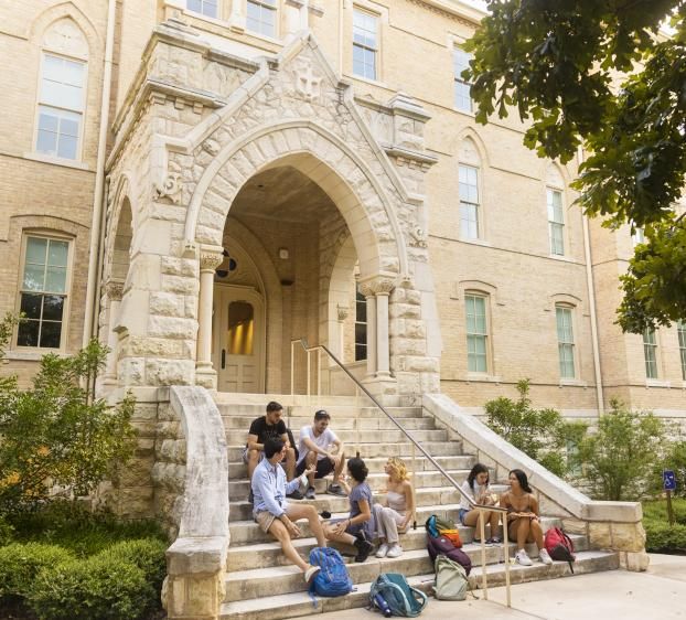 A group of students sit and hang out on the steps of Holy Cross Hall.