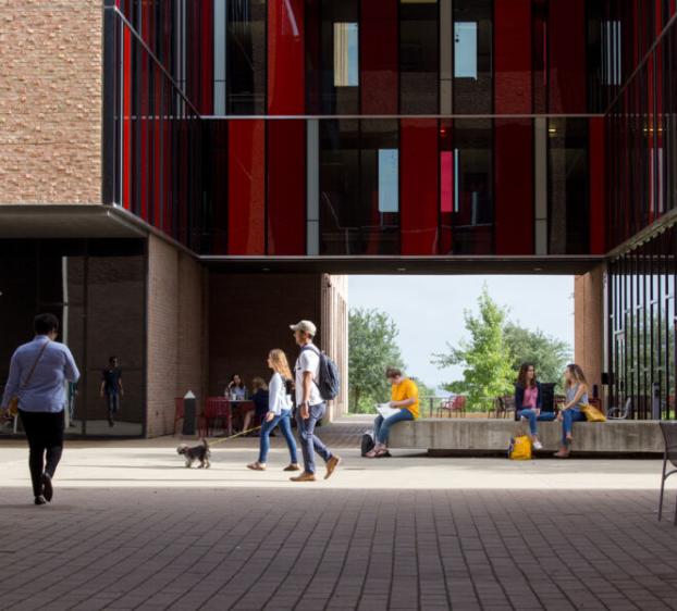 People walk through or sit in the courtyard patio space of The Village.