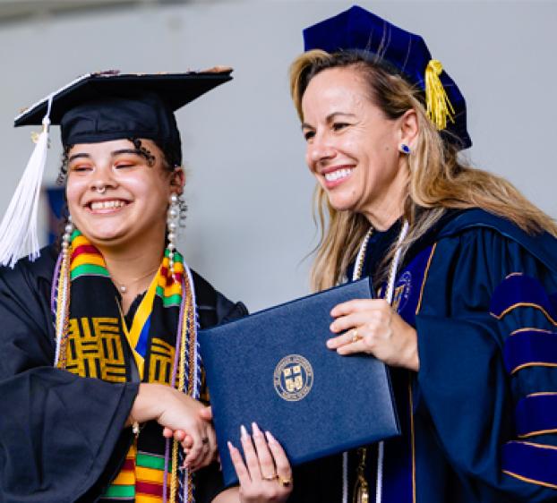 Kaitlynn Devitt (left) receives her degree at graduation. Devitt was awarded the Michele Kay Outstanding Journalist Award for her photojournalism work. 