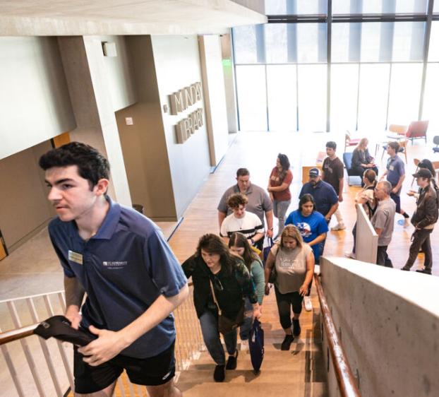 A student leading a campus tour group up the stairs of the library