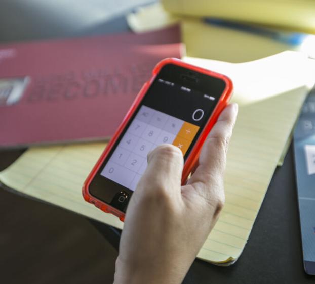 A student holding up a phone with the calculator app