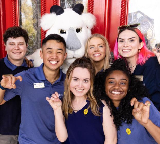 St. Edward's students with Topper the goat mascot in front of the red doors.