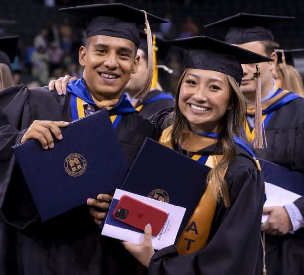 St. Edward's graduates in cap and gown show off their diplomas