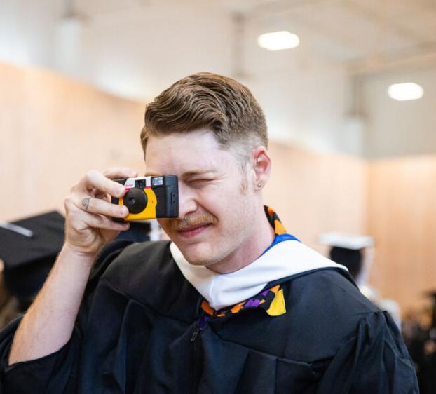 A student takes a photo of his friends with a disposable camera
