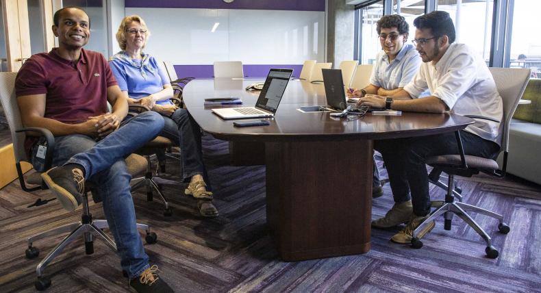 2 students sitting at a board room table at their internship with two supervisors.