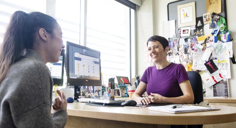 Staff member advises student in university office.